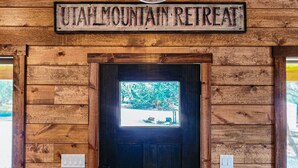 Un letrero de madera que dice "UTAH MOUNTAIN RETREAT" sobre una puerta con un ventanal.