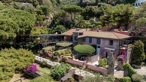 A hillside villa with terraced gardens, stone walls, and a mix of Mediterranean architecture.