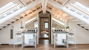 Un dormitorio en ático con techos altos, tragaluces y suelo de madera.
