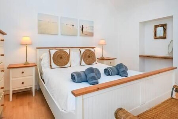 Un dormitorio con una cama, dos mesitas de noche, una lámpara y una estantería en la pared.