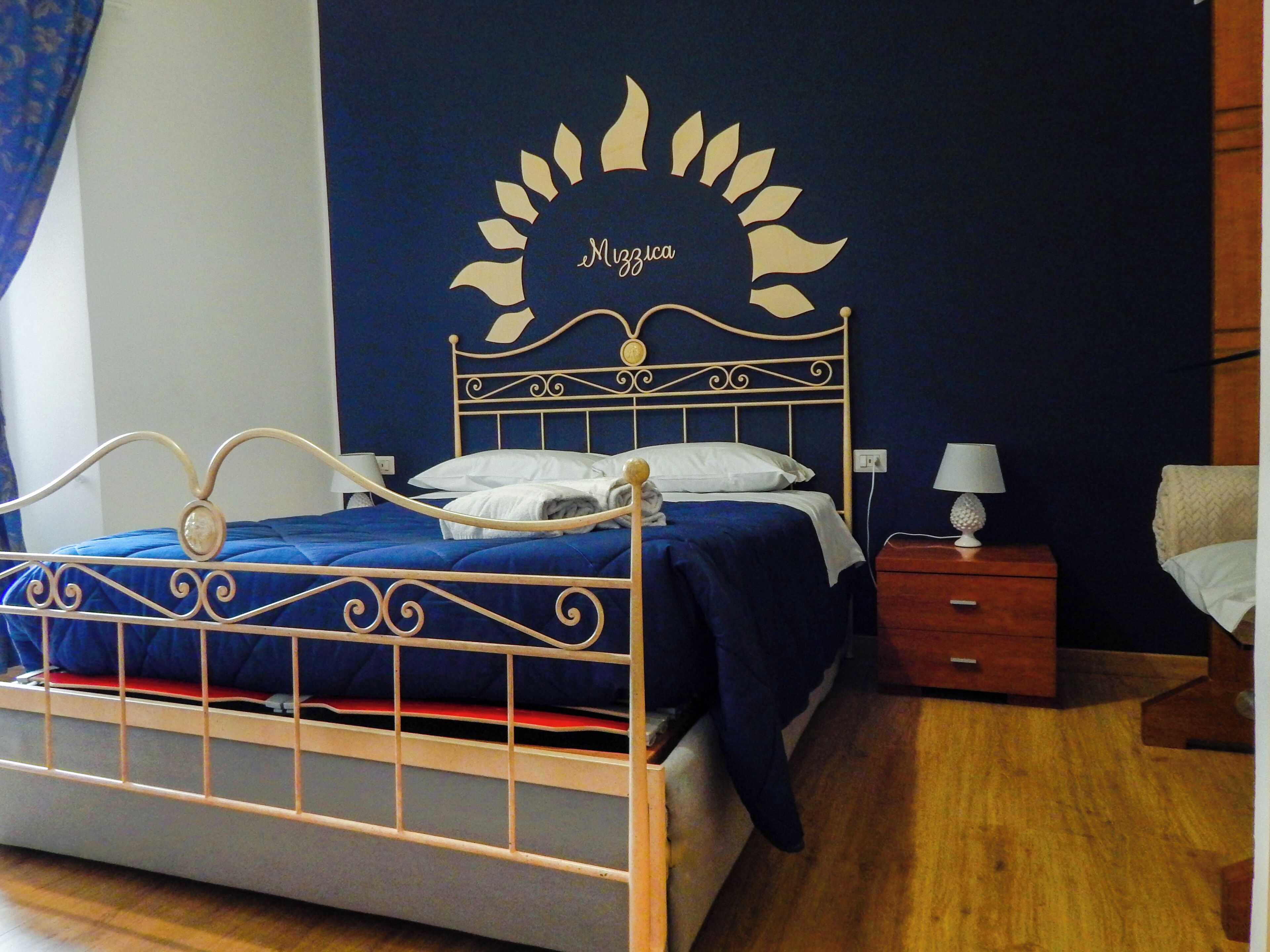 Ein Schlafzimmer mit Bett, Nachttisch, Lampe und Wandbild.