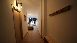 Un pasillo estrecho con suelo de madera, un banco y una cama al fondo.