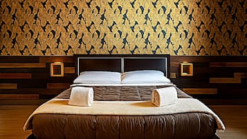 A modern bedroom with a large bed, wooden headboard, and a patterned wallpaper.
