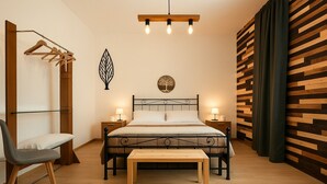 Un dormitorio con cama, mesitas de noche, una silla, lámpara colgante y un panel de madera en la pared.