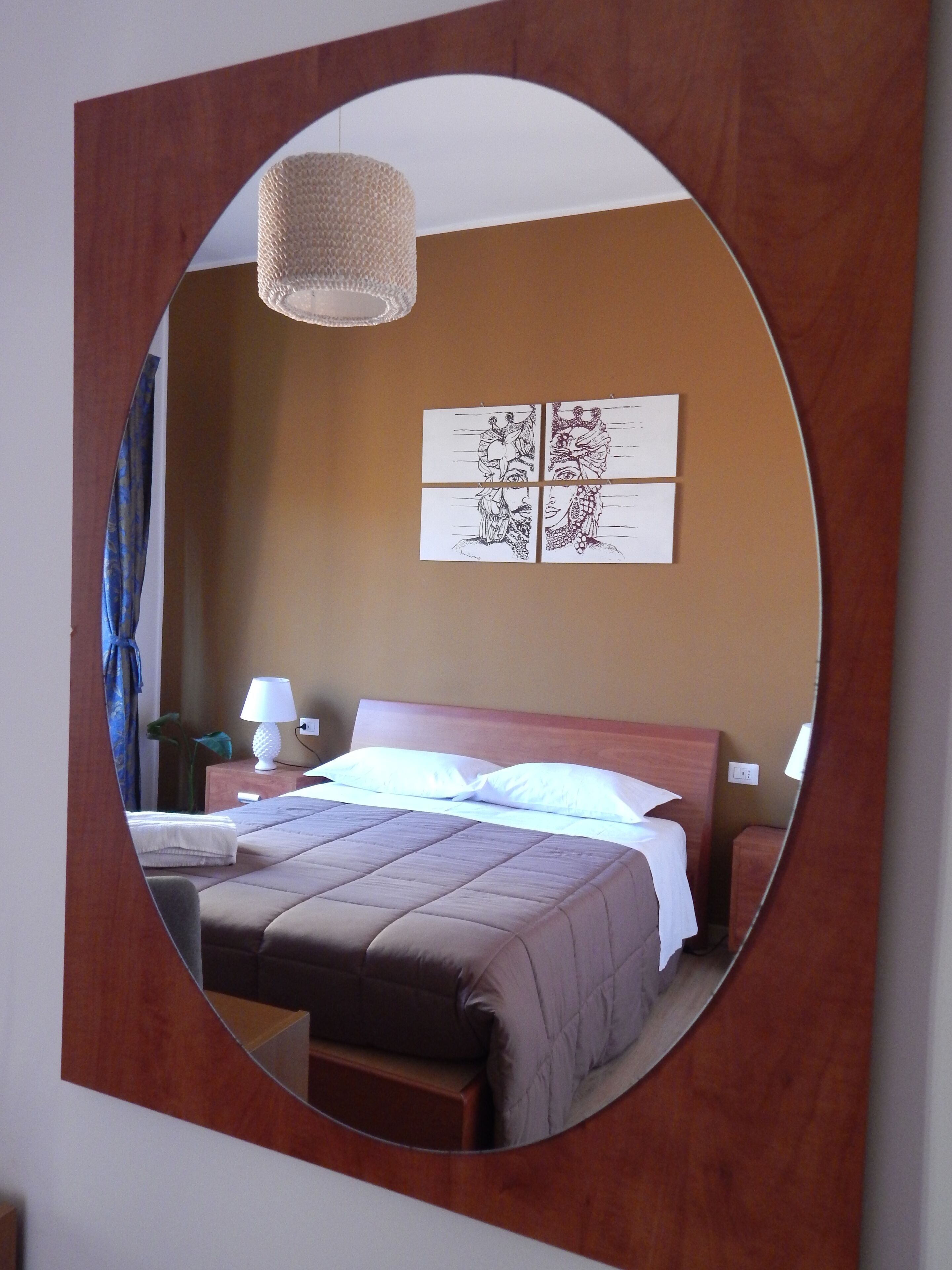 Une chambre d’hôtel équipée d’un lit, d’une table de chevet, d’une lampe et d’un miroir fixé au mur.