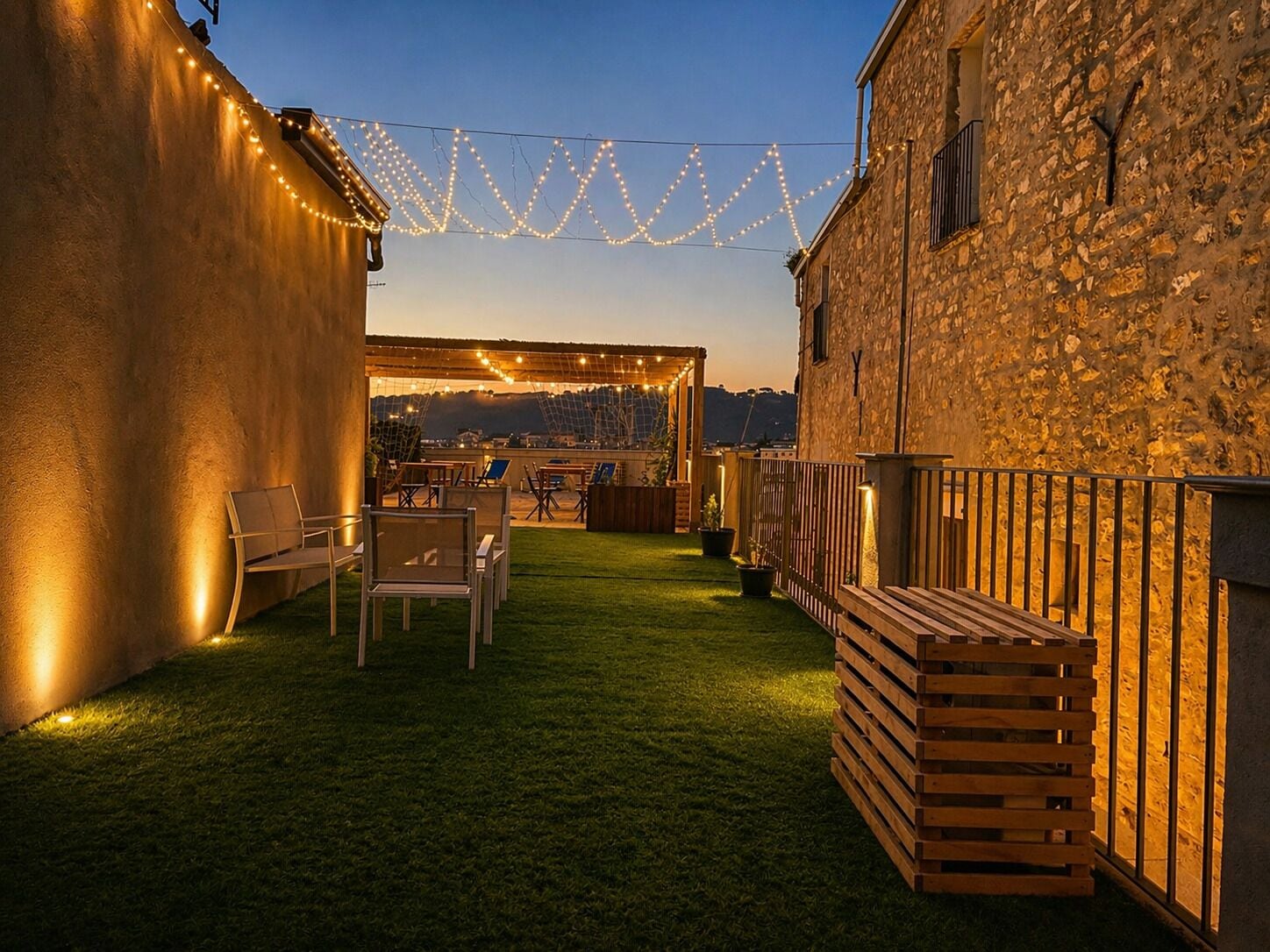 Un patio al aire libre con un banco de madera, sillas y una mesita.