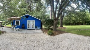 Ein blaues Gebäude mit einem Stern an der Vorderseite, eine Terrasse mit Tisch und Stühlen sowie ein kleiner Garten.