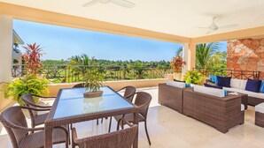 Ein geräumiger Balkon mit Esstisch, Korbmöbeln und Topfpflanzen.