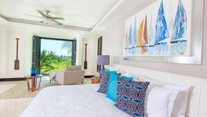 Ein Hotelzimmer mit einem Bett, einem Sessel, einem Tisch und einem Gemälde von Segelbooten.