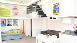 A modern apartment with a dining area, kitchen, and a staircase leading to an upper level.