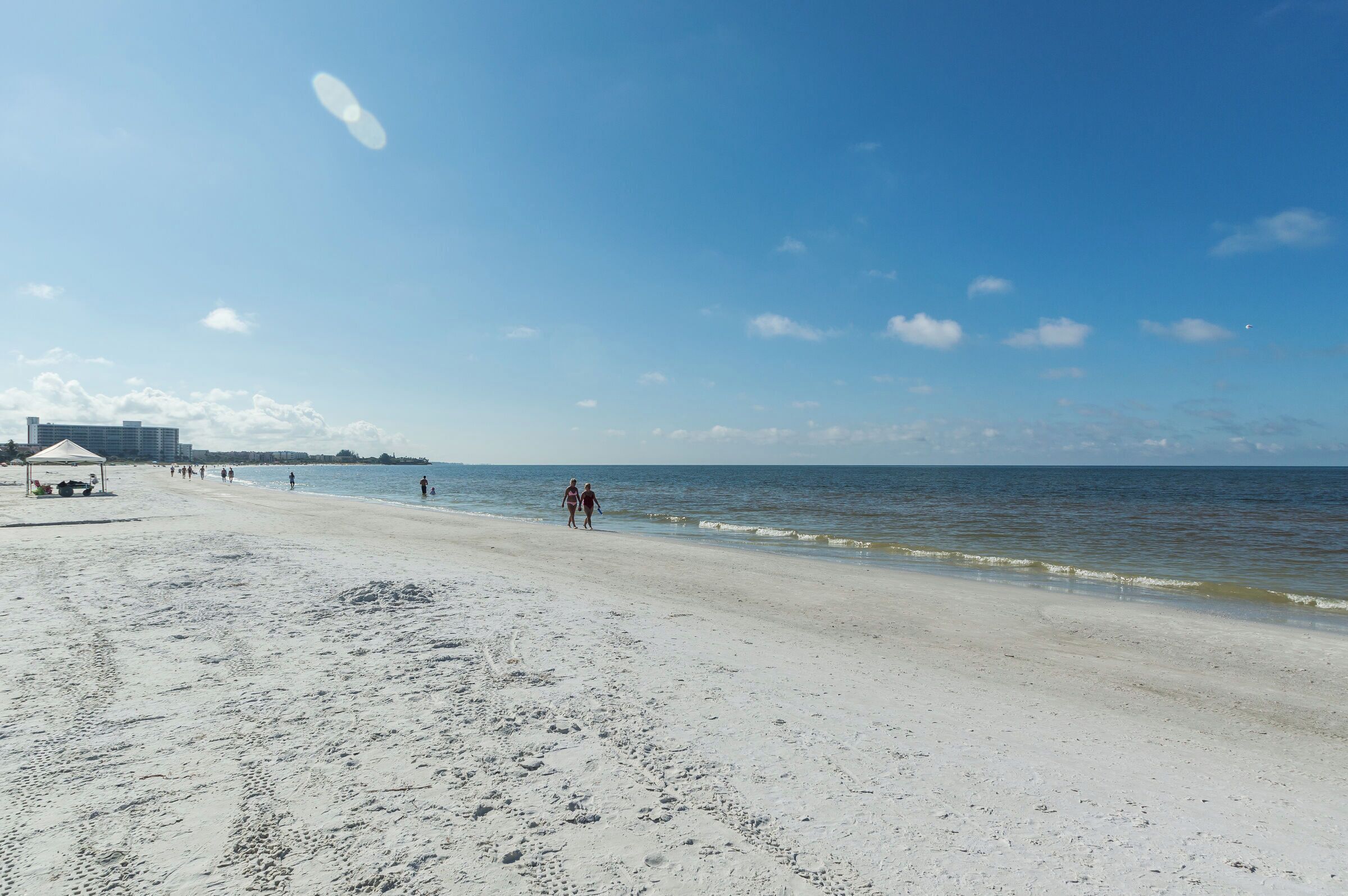A beach with a pavilion, a clear sky, and a calm sea.
