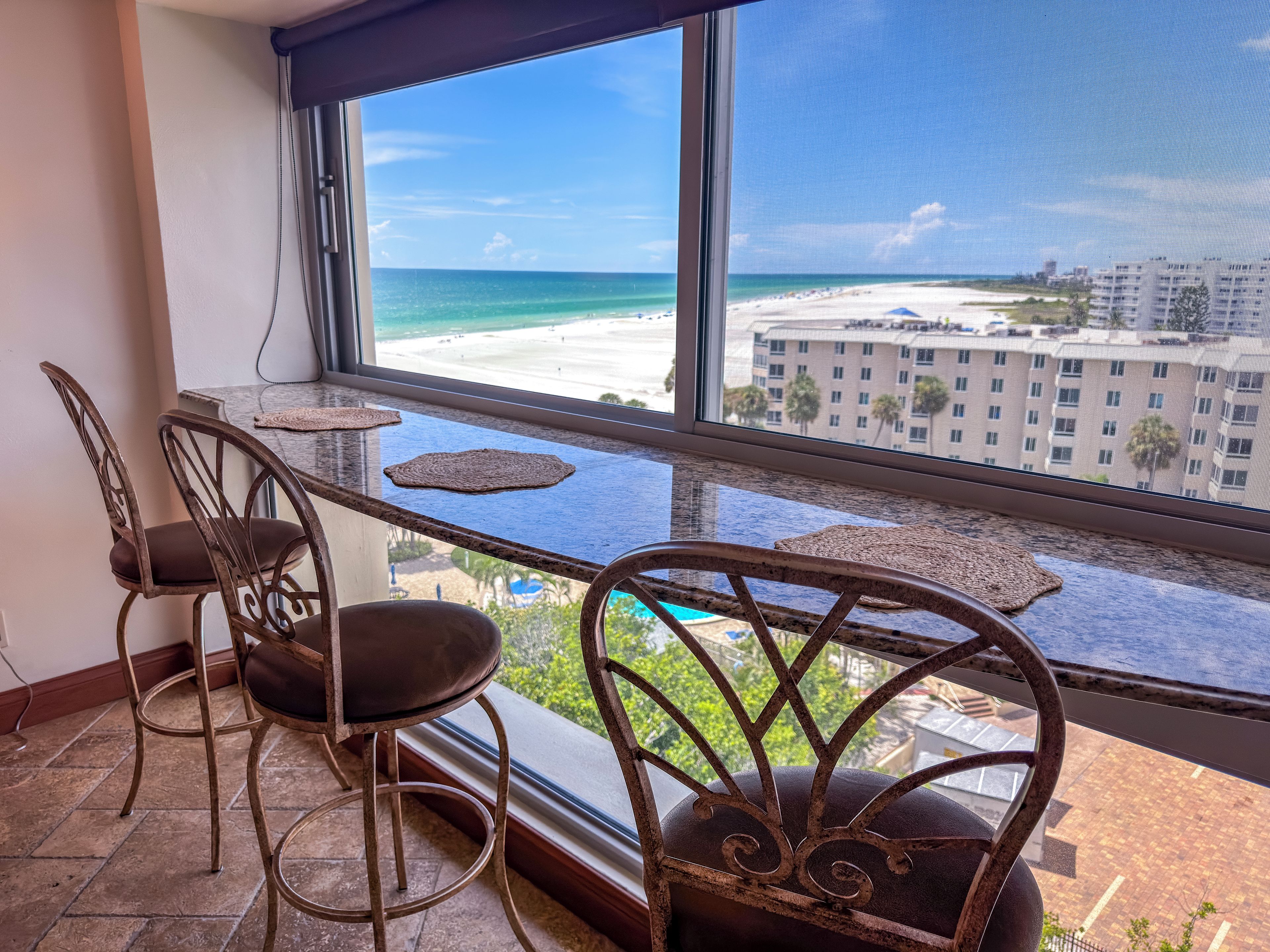 A balcony with a view of a beach and hotel buildings.