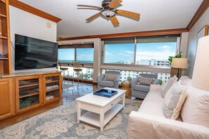 A living room with a television, seating area, and large windows offering a view of the city. - Unit 84- 1 Bedroom 1 Bathroom Condominium with Partial North Views. (Sarasota)