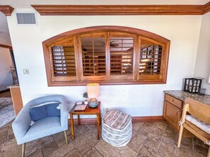 A room with a large arched window, a small table with a lamp, a chair, and a cabinet. - Unit 84- 1 Bedroom 1 Bathroom Condominium with Partial North Views. (Sarasota)
