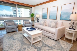 A modern living room with a sofa, armchairs, a coffee table, and a view of a building through large windows. - Unit 84- 1 Bedroom 1 Bathroom Condominium with Partial North Views. (Sarasota)