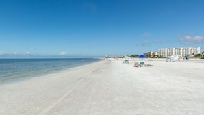 A beach with clear skies, a sandy shore, and a hotel in the background. - Unit 84- 1 Bedroom 1 Bathroom Condominium with Partial North Views. (Sarasota)