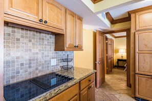 A kitchen with wooden cabinets, a tiled backsplash, and a granite countertop.