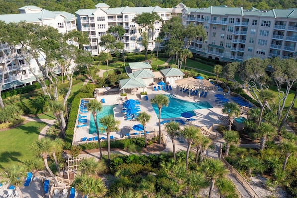 A resort with multiple buildings, a central pool area with sun loungers, and surrounding greenery. - 2 Bedroom Second Floor Oceanfront Condo (Hilton Head)