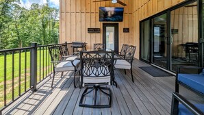 A wooden deck with outdoor furniture, a ceiling fan, and a TV mounted on the wall.
