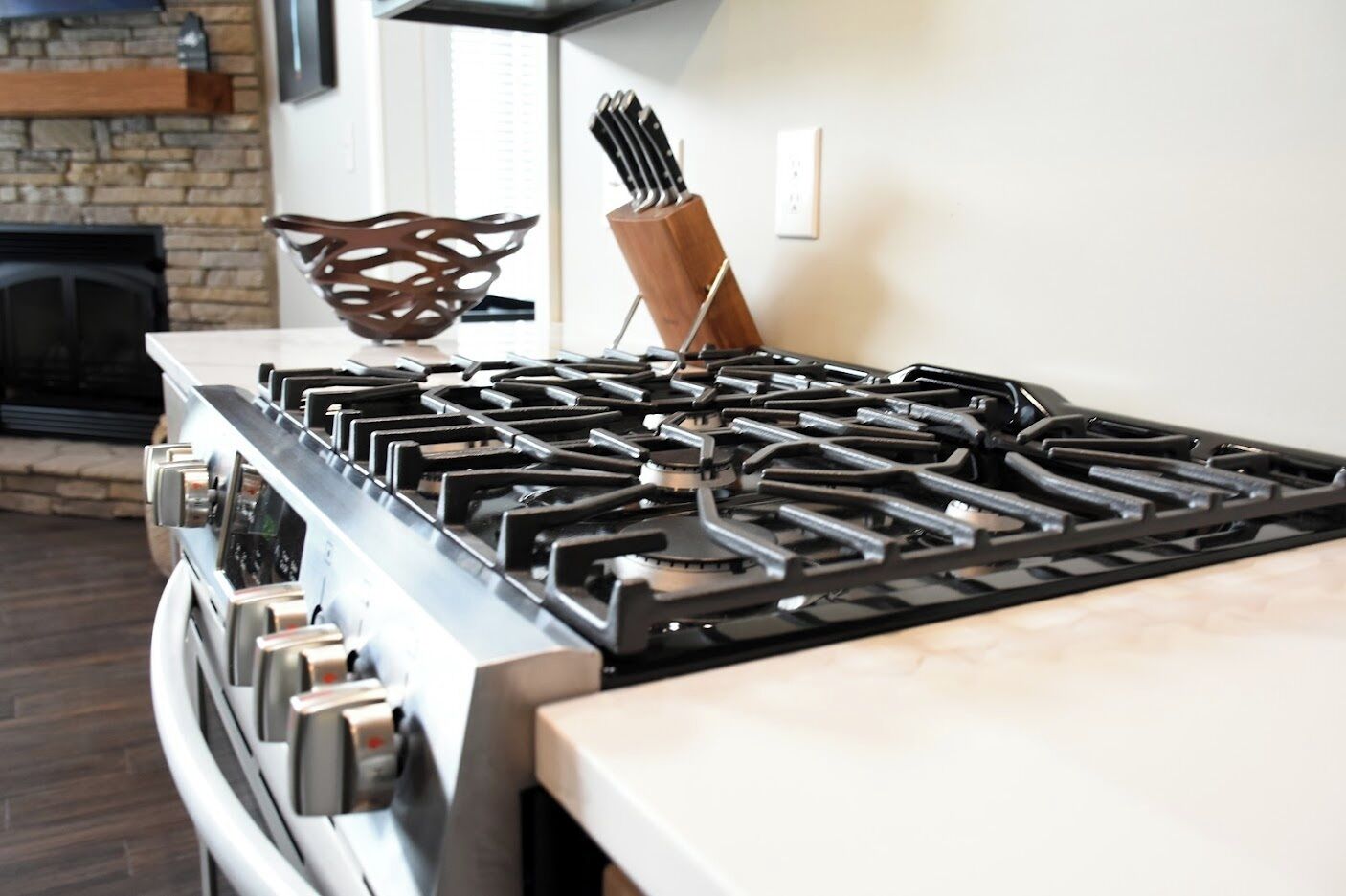 A modern kitchen with a stainless steel stove, a wooden cutting board, and a knife block.