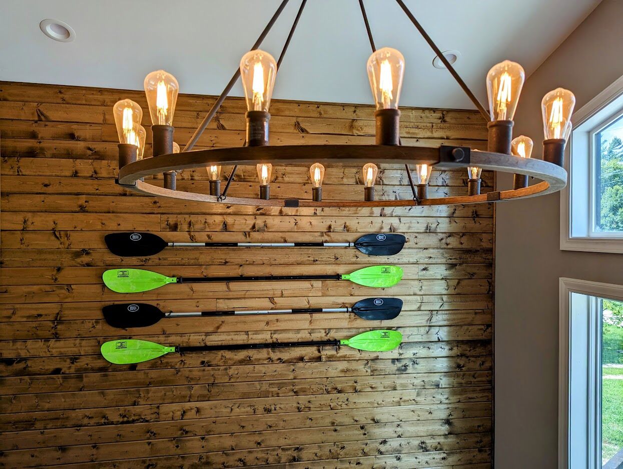 En trævæg med en rund lampe og flere kajakker stablet horisontalt.