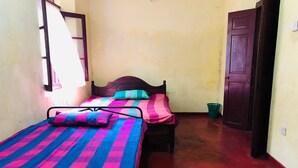 A small, narrow room with two single beds, each with a colorful striped bedspread.