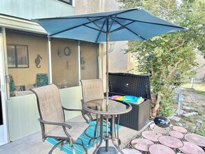 Un espace patio avec une table ronde, deux chaises et un parasol bleu.