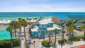 A beachside hotel with a pool, palm trees, and a view of the ocean. - Pet Friendly • Walk to Beach • 11 Pools • Sleeps 6 (Panama City Beach)