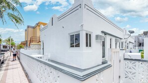 Un edificio blanco con balcón, una reja y un ventanal pequeño.