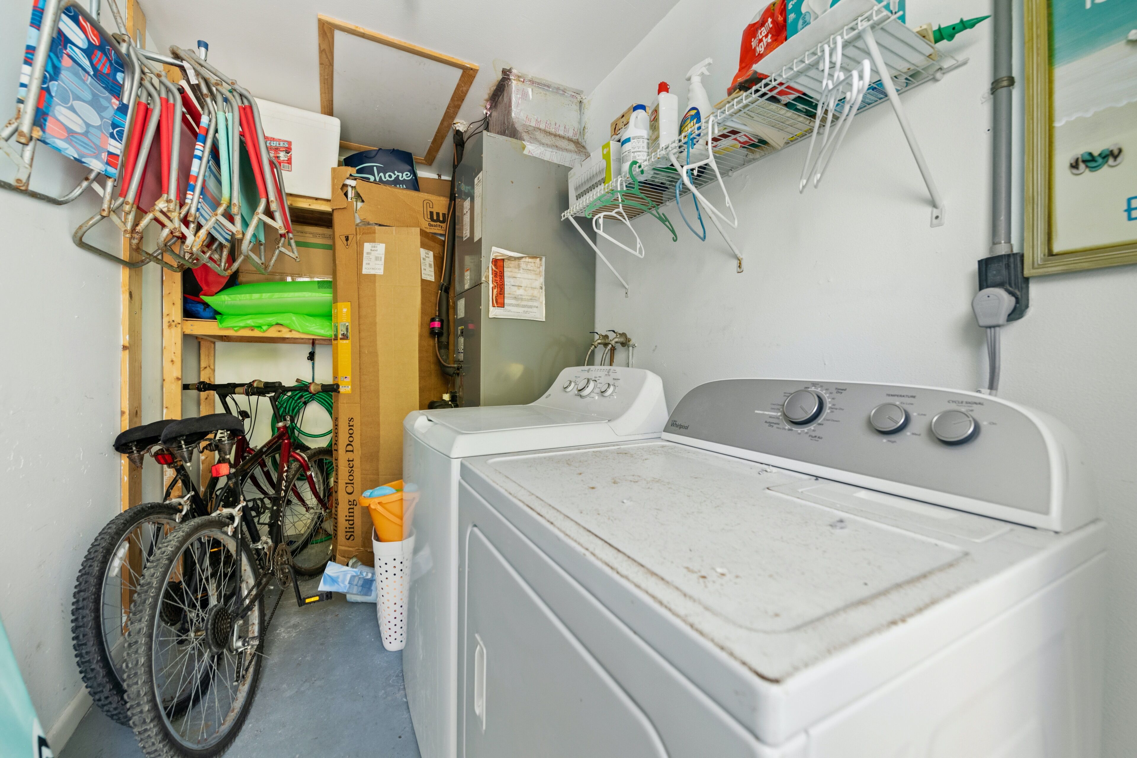 A laundry area with a washing machine, a bicycle, and a shelf with cleaning supplies.