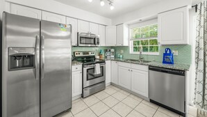 A modern kitchen with stainless steel appliances, white cabinets, and a tiled backsplash.