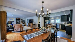 Uma sala de estar ampla com uma mesa de jantar de madeira, um sofá confortável e um lustre.