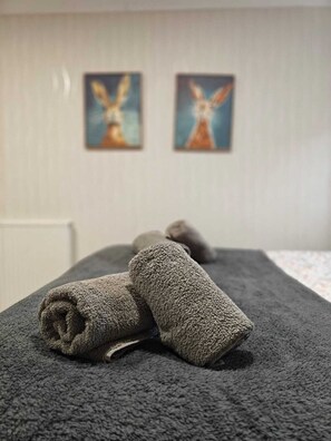 A room with a massage table, two rolled-up towels, and two paintings on the wall. - The Jays Guest House (Aberdeen)