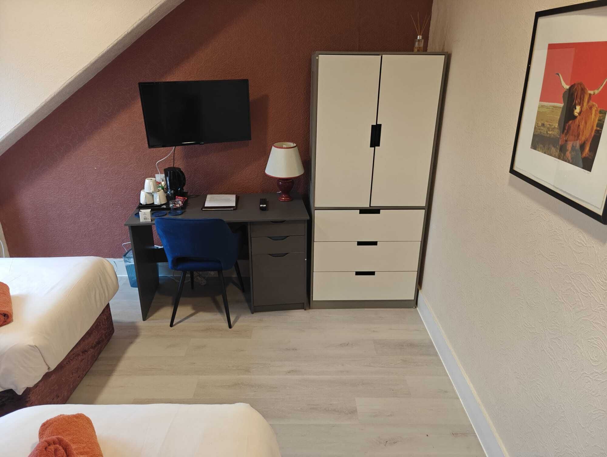 Habitació d'hotel amb llit, escriptori, cadira, televisió i armari.