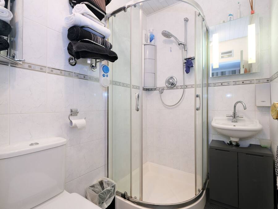A modern bathroom with a glass-enclosed shower, a toilet, a sink, and a towel rack with neatly folded towels.