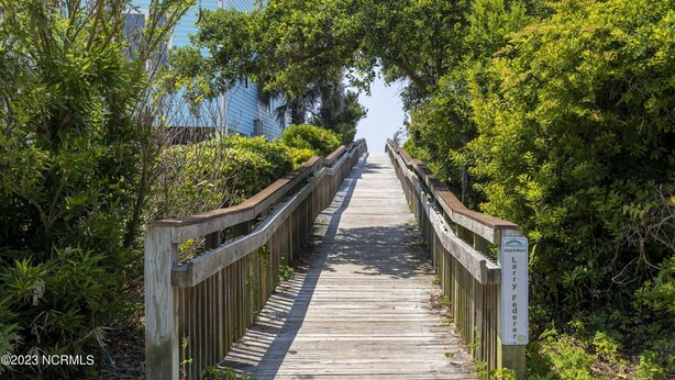 A wooden boardwalk leading to a house surrounded by lush greenery. - Sleeps 5! 2 BR, 2.5BA Townhome-Walk to Beach & Dining – Your Escape Awaits! (Emerald Isle)