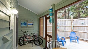A patio with a wooden table and chairs, a bicycle, and a wooden fence. - Sleeps 5! 2 BR, 2.5BA Townhome-Walk to Beach & Dining – Your Escape Awaits! (Emerald Isle)