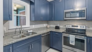 A kitchen with blue cabinets, a stainless steel sink, a microwave, and an oven. - Sleeps 5! 2 BR, 2.5BA Townhome-Walk to Beach & Dining – Your Escape Awaits! (Emerald Isle)