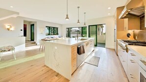A modern kitchen with a large island, pendant lighting, and a view to the outdoors. - Rooftop Deck/Ocean Views/A/C/Close To All (La Jolla)