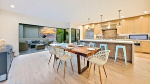 A modern kitchen with a dining area, wooden flooring, and light blue bar stools. - Rooftop Deck/Ocean Views/A/C/Close To All (La Jolla)