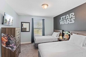 Une chambre à coucher sur le thème de Star Wars, avec deux lits, une armoire, une affiche de Star Wars et un autocollant mural.