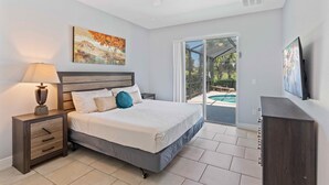Un dormitorio con cama, mesita de noche, lámpara y una obra de arte.