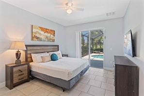 A bedroom with a bed, nightstand, lamp, artwork, and a view of a pool through a sliding glass door. - Free Water Park * Lazy River * Game Room (Davenport)