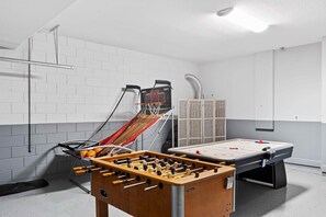 Une pièce équipée d’un baby-foot, d’une table de ping-pong et d’un espace délimité par un filet.