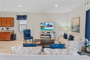 A living room with a television, a sofa, a coffee table, and a cabinet. - Lake View! 8BR Home w Private Pool Spa near Disney (Kissimmee)