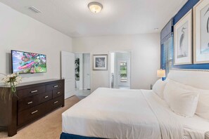 Une chambre à coucher comprenant un lit, une commode, un téléviseur et des œuvres d’art encadrées accrochées au mur.