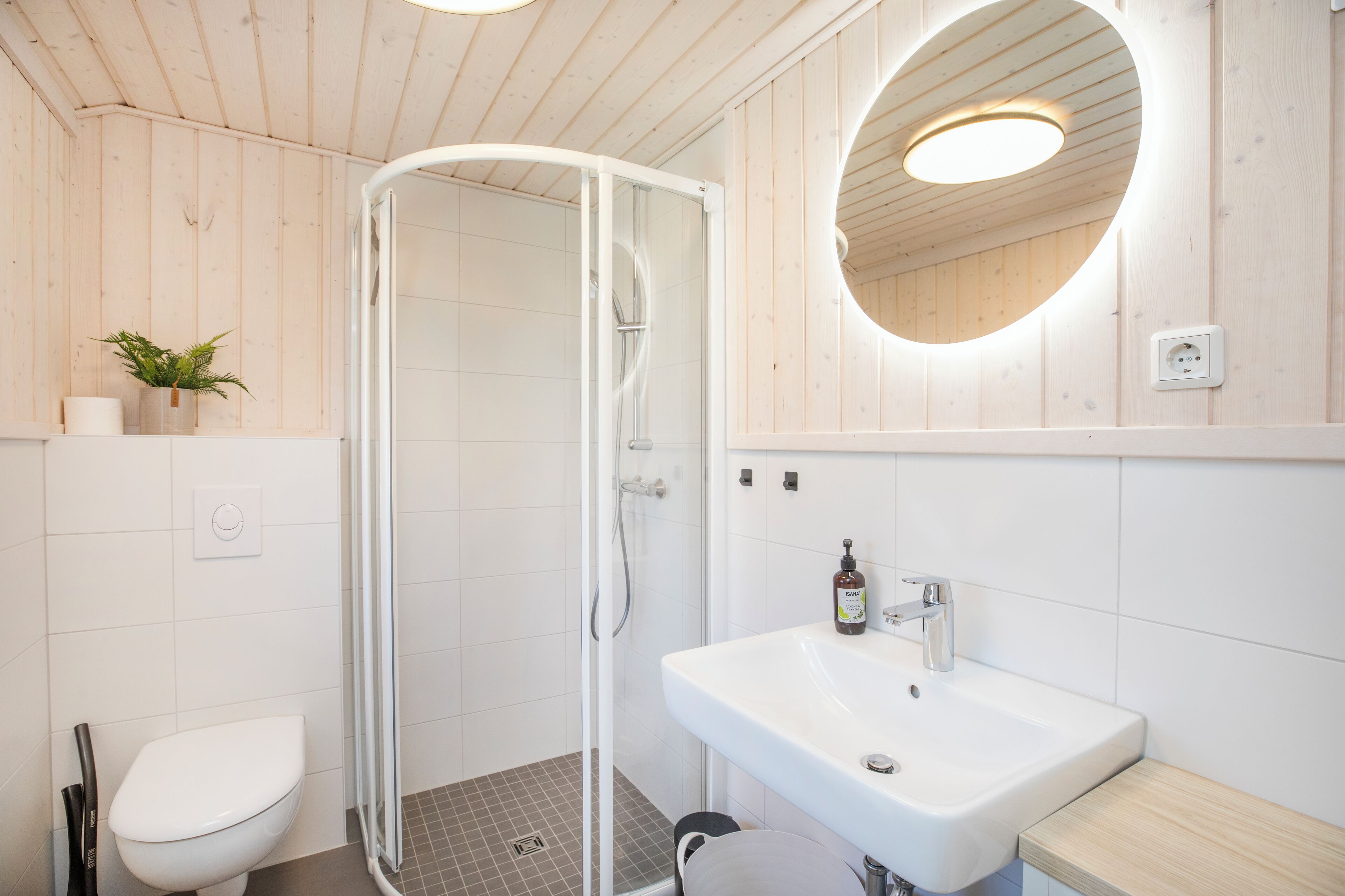 Een moderne badkamer met douche, toilet en wastafel.