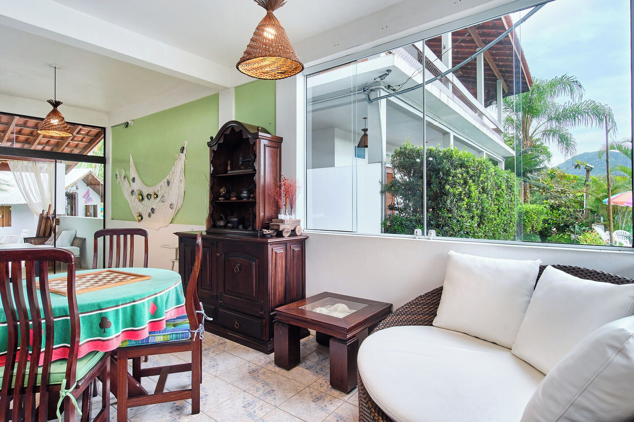 A cozy living room with a dining table, chairs, a sofa, and a large window offering a view of greenery and a building.