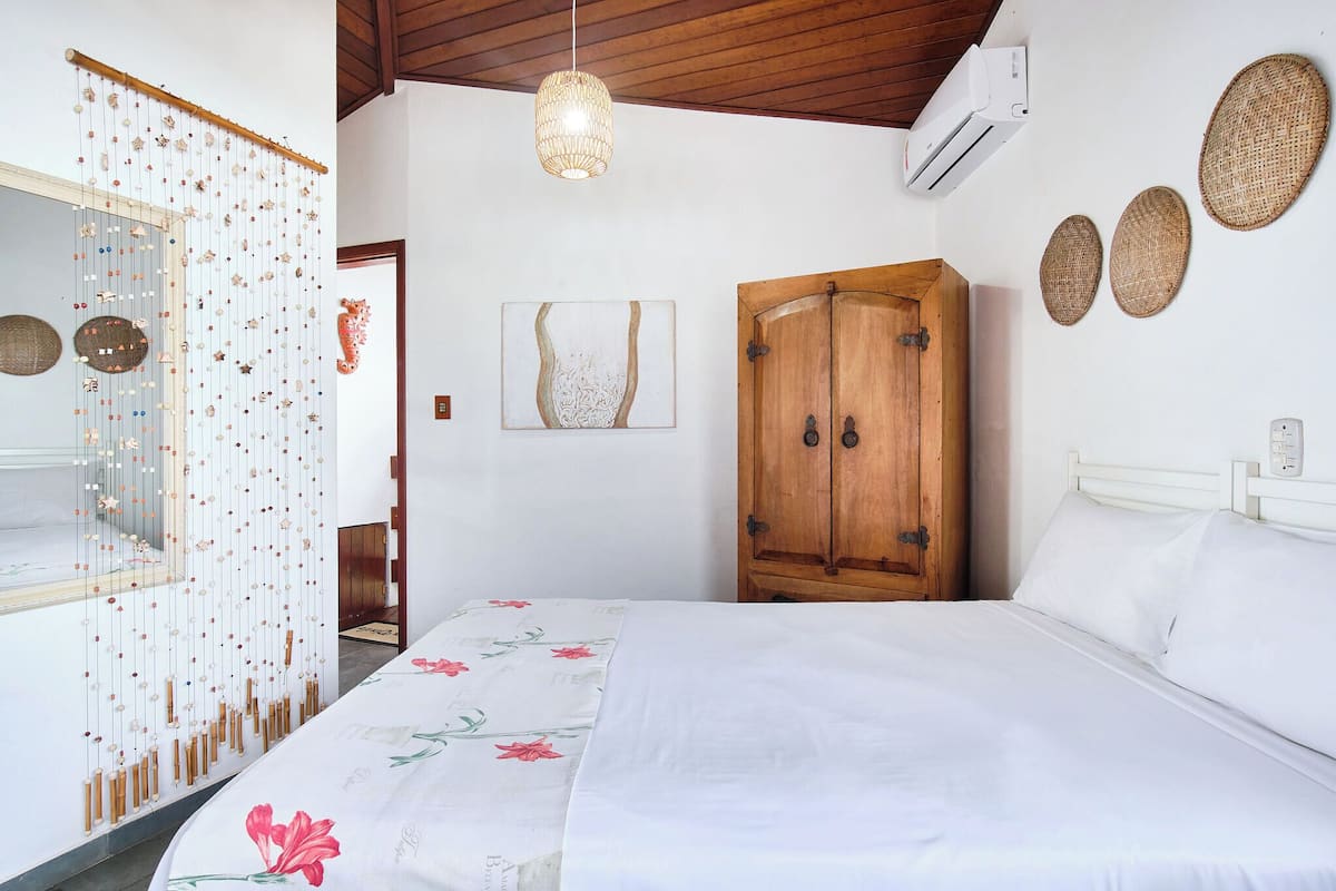 Een slaapkamer met een bed, een houten kledingkast, wanddecoratie en een decoratief hangobject.