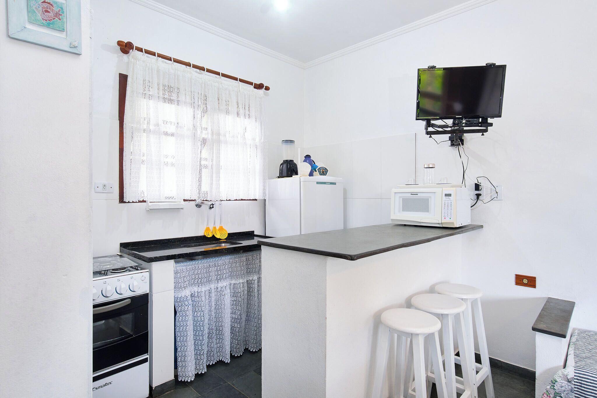 A compact kitchen with a stove, microwave, and bar stools.